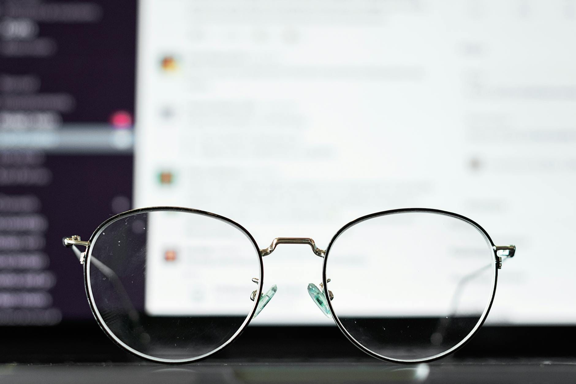 Okulary na klawiaturze laptopa z rozmytym ekranem w tle