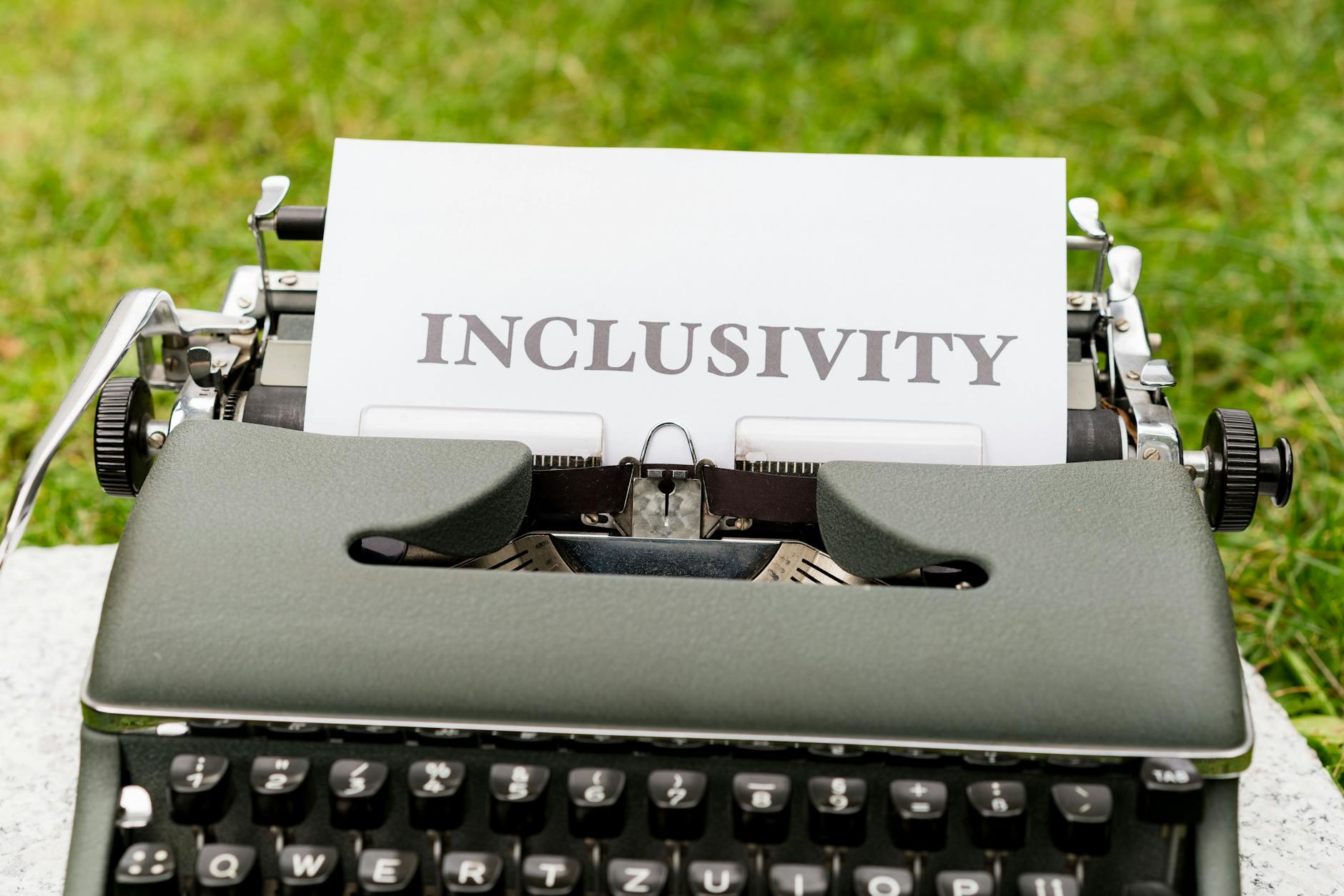 Stara maszyna do pisania z kartką inclusivity na zielonym tle