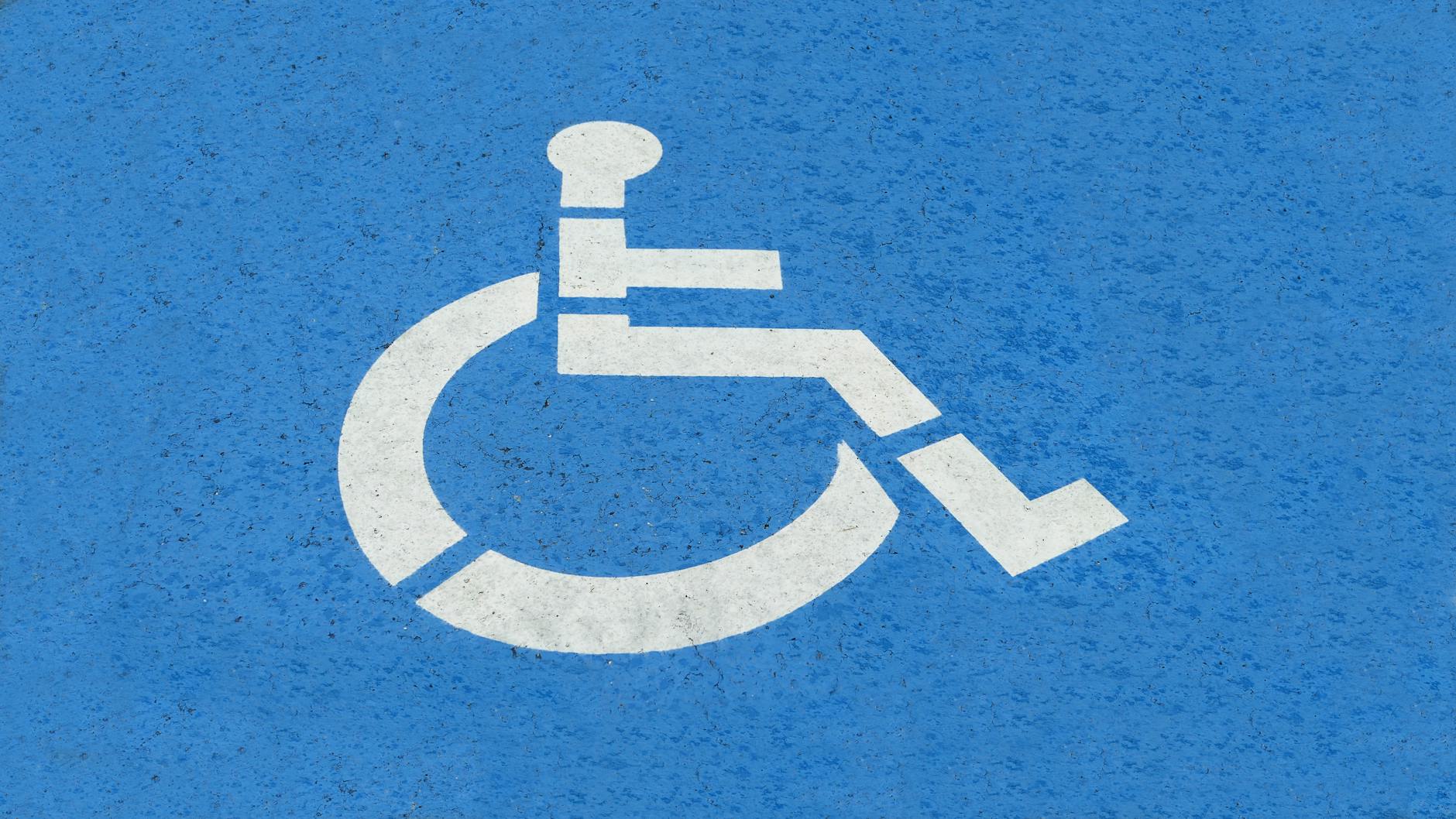 Symbol miejsca parkingowego dla osób z niepełnosprawnościami na niebieskiej nawi