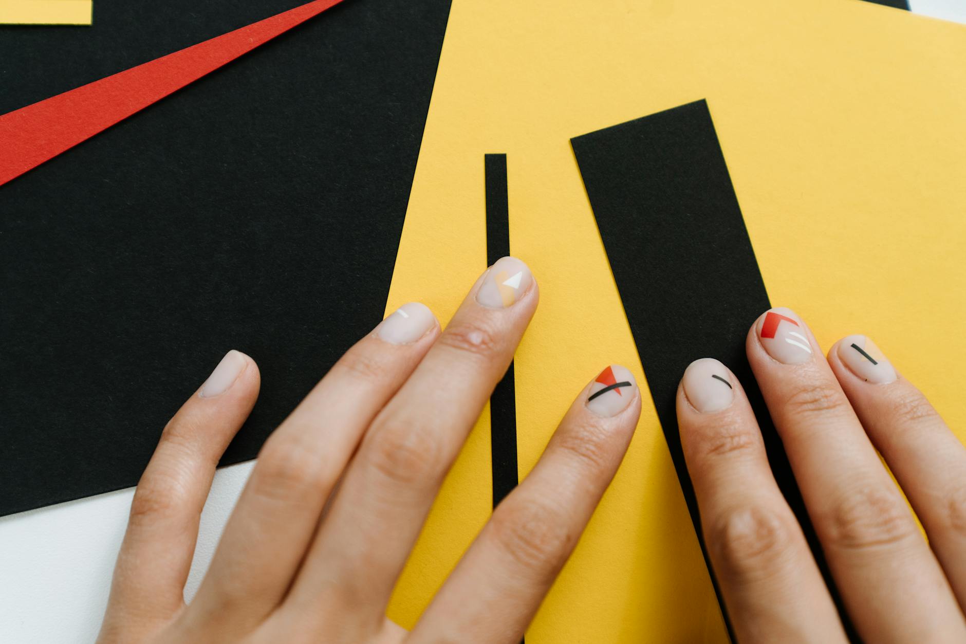 Zbliżenie jesiennego manicure z geometrycznym wzorem na tle żółci i czerni