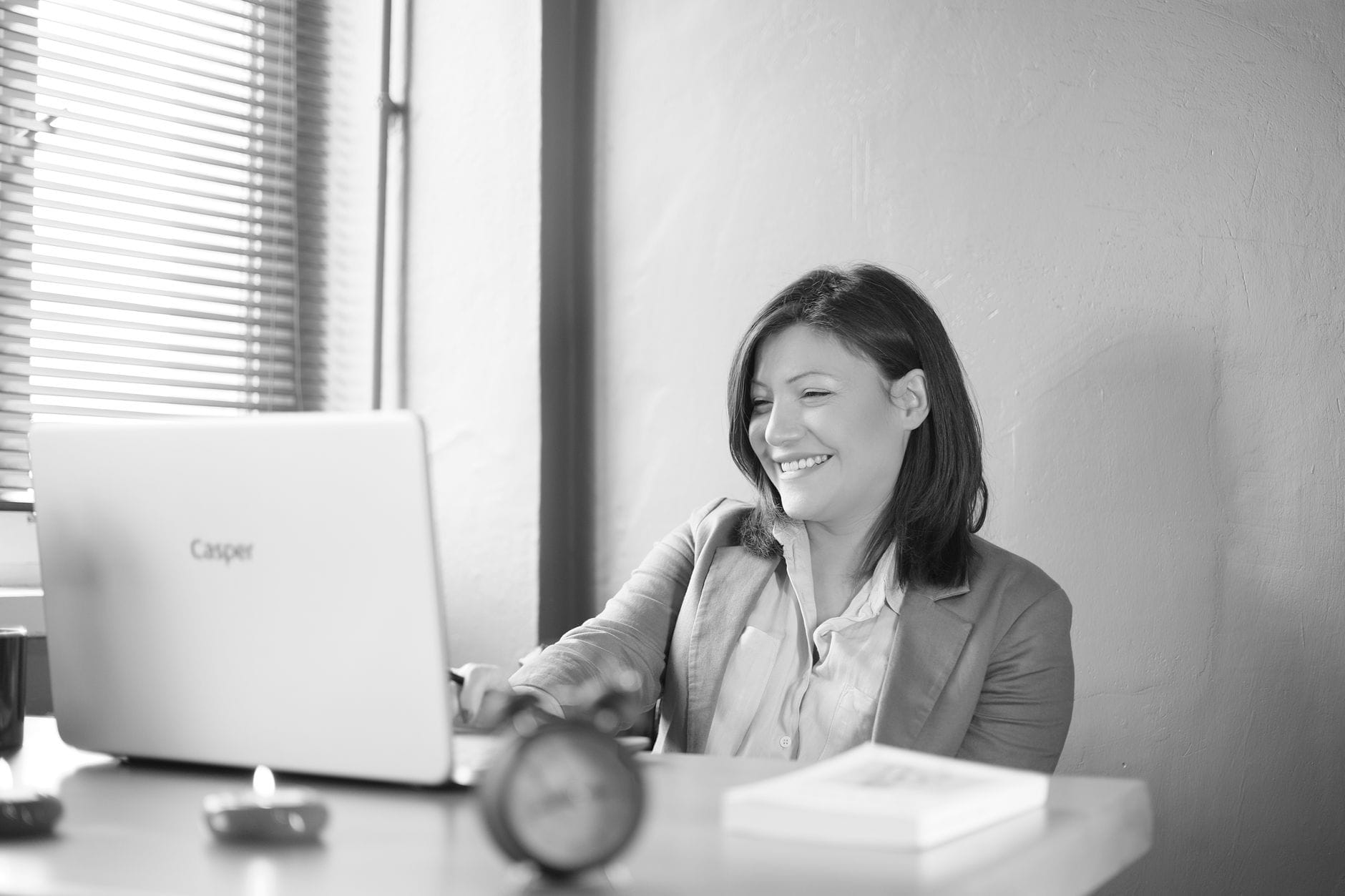 Uśmiechnięta bizneswoman pracuje przy laptopie w jasnym biurze