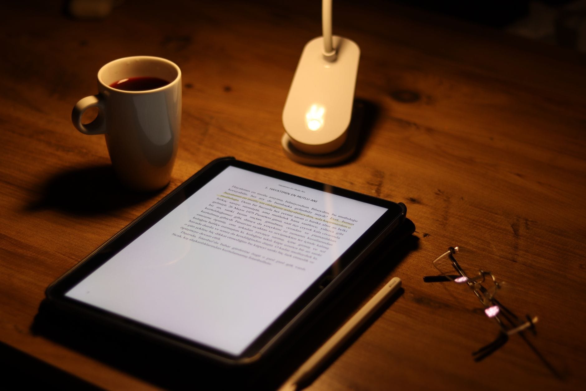 Tablet z otwartym dokumentem PDF obok kawy i okularów na biurku