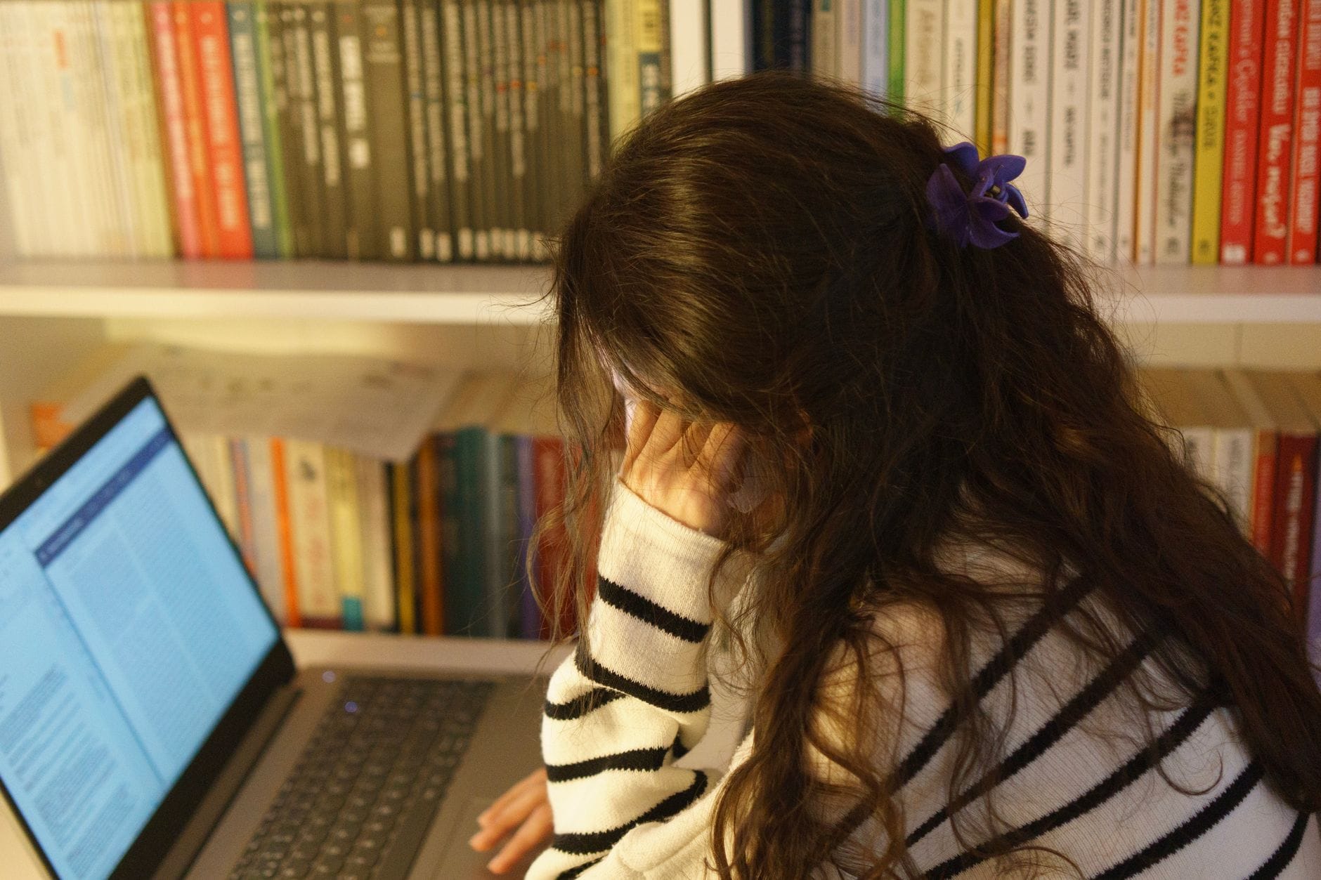 Zdalne lekcje a zmęczenie słuchowe: jak dbać o koncentrację przy ciągłej pracy z syntezą mowy Zestresowana studentka w bibliotece przed laptopem podczas nauki
