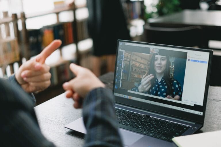 Nauczycielka uczy języka migowego studentkę podczas wideorozmowy na laptopie