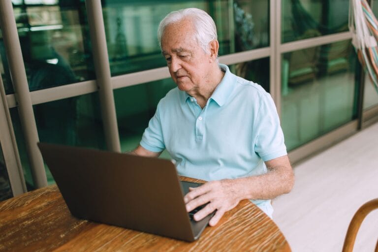 Starszy mężczyzna korzystający z laptopa w pomieszczeniu