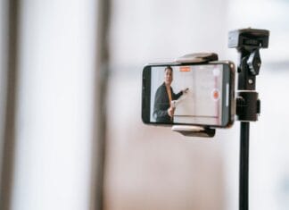 Czy uczelnia musi zapewnić dostępne materiały i platformę e-learningową? Wykładowca prowadzący zajęcia online przez smartfon na statywie