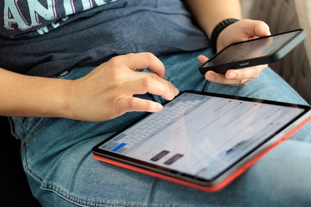 Zbliżenie na osobę korzystającą z tabletu i smartfona w pomieszczeniu Zbliżenie na osobę korzystającą z tabletu i smartfona w pomieszczeniu
